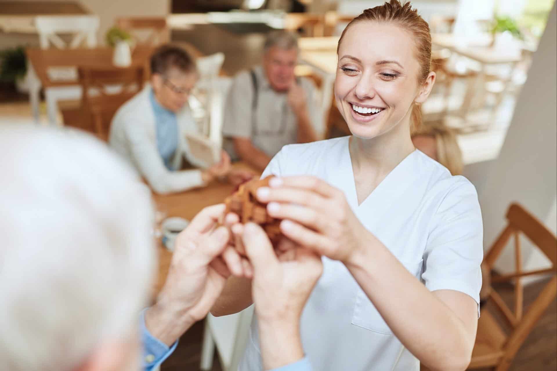 Caregiver assisting elderly person with hand massage in a warm, welcoming environment.