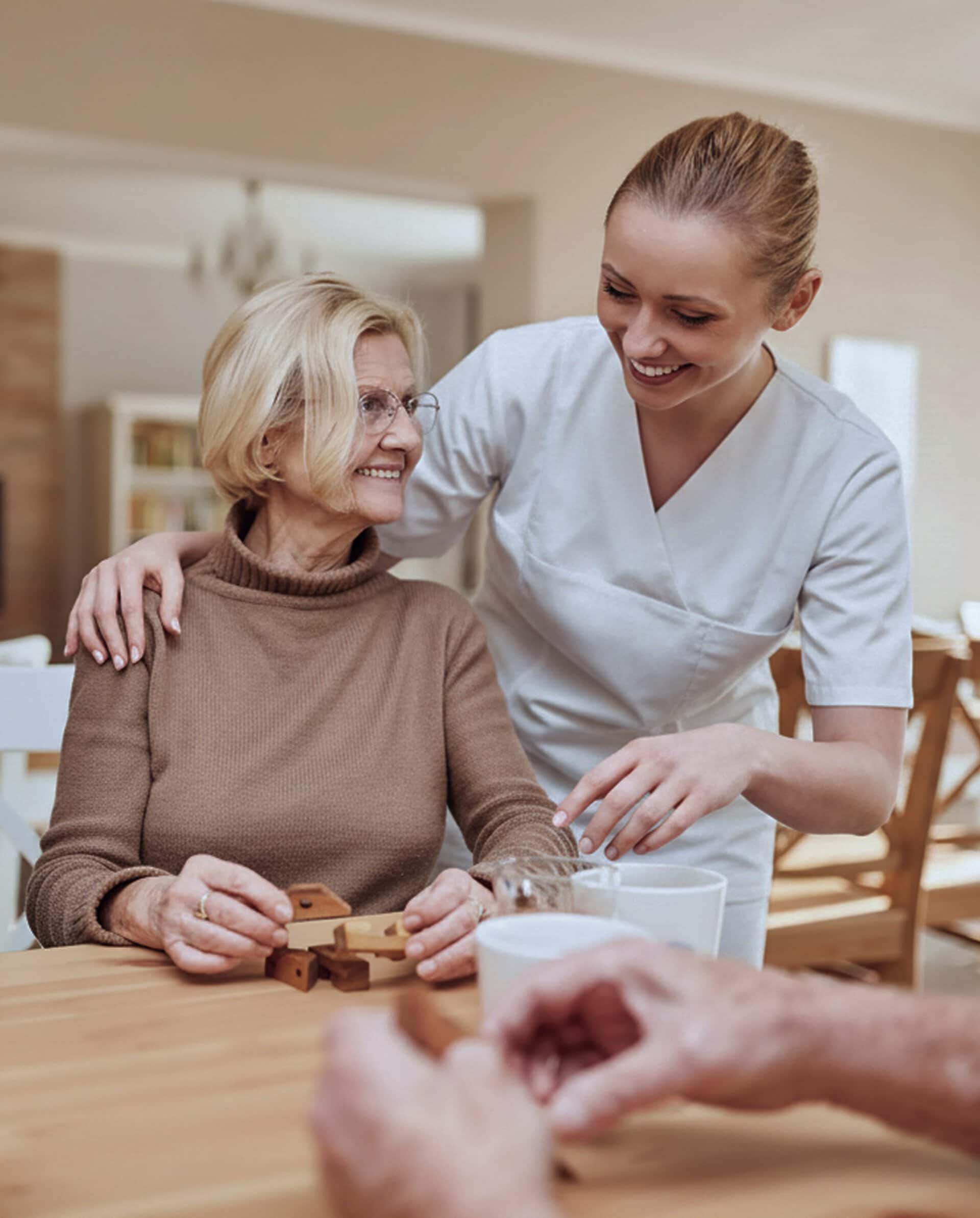 Caregiver assisting elderly woman happily
